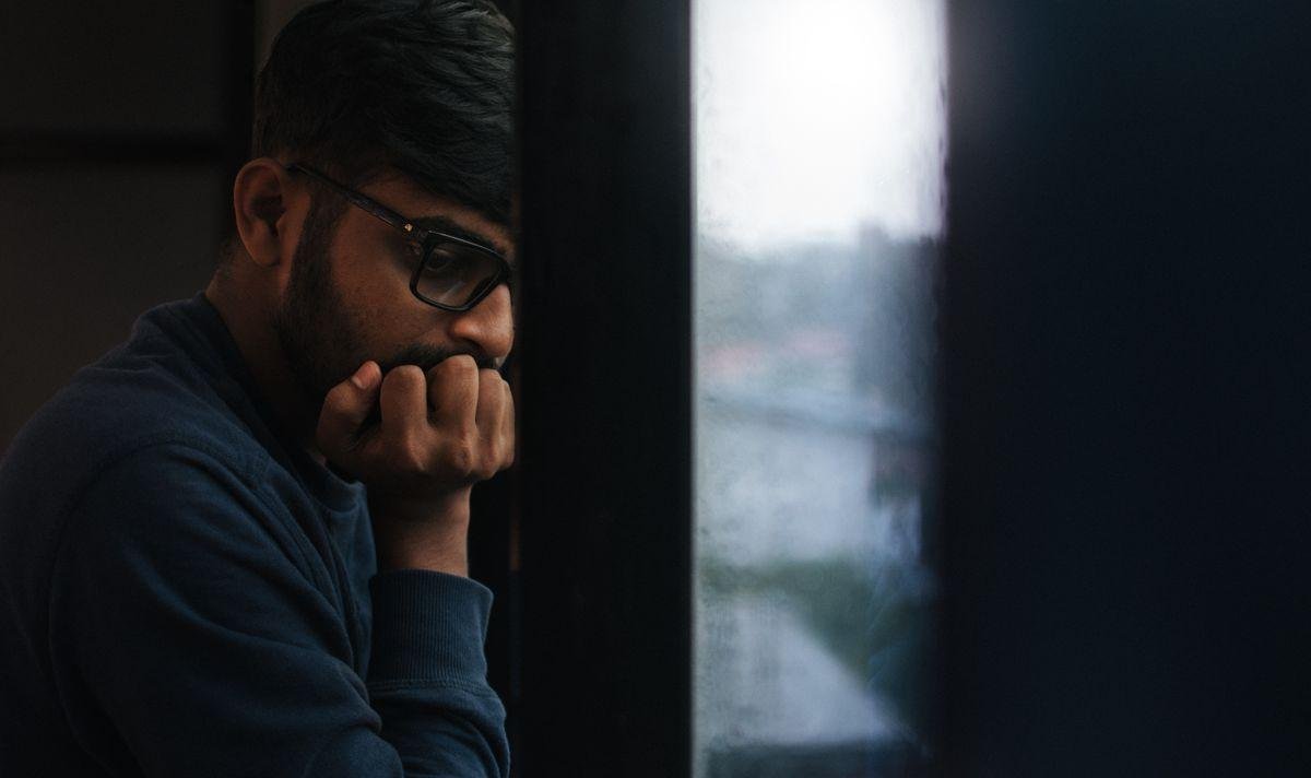 Person looking out a rain-streaked window while coping with PTSD symptoms